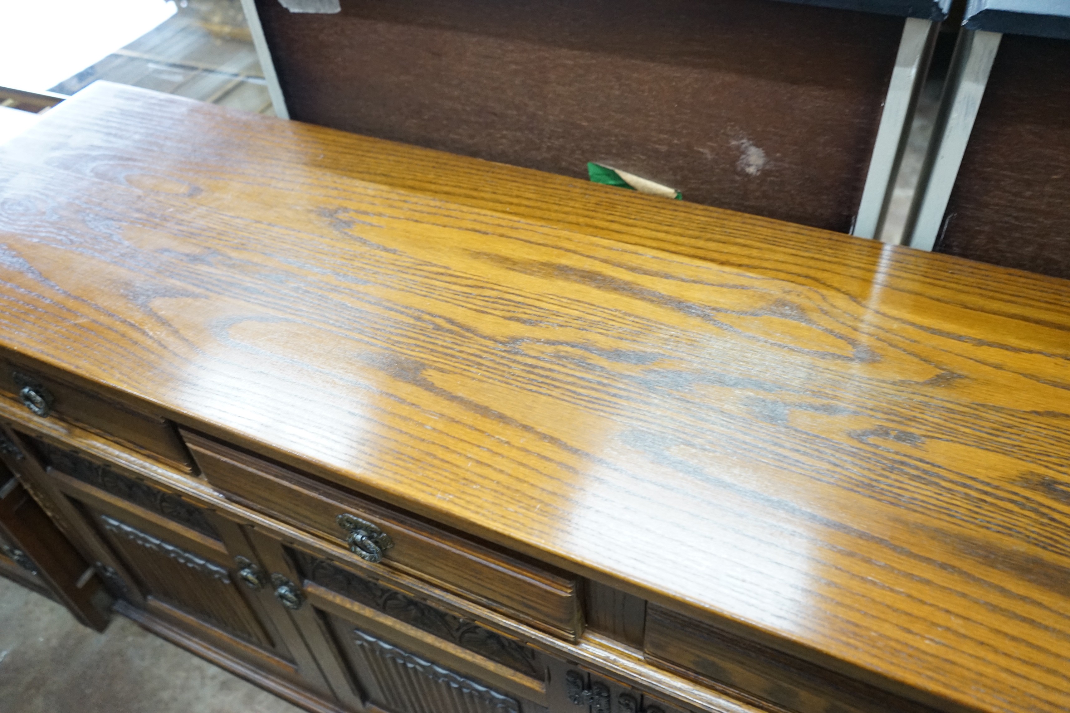 A reproduction 18th century style carved and linen fold moulded oak sideboard width 187cms, depth 44cms, height 87cms.